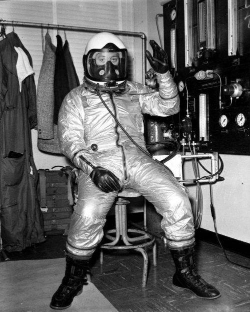 On May 3, 1958, the configuration of the S794-6 suit to be delivered to Crossfield was frozen during a meeting in Worcester between representatives of David Clark Company, North American, and the USAF. The decision was somewhat premature since the suit configuration was still in question during a meeting 3 months later at Wright Field. This indecision had already resulted in a 2-month delay in delivery, and the need for further tests was apparent. Fortunately, in a perverse way, the entire X-15 program was running behind schedule, so the delay in the suit was not critical—yet.

 

Nevertheless, the X-15 Project Office advised the newly assigned chief of the Aero Medical Laboratory, Col. John P. Stapp, that the suit delays might postpone the entire X-15 effort. To maintain the schedule, the X-15 program needed to receive Crossfield’s suit by January 1, 1959, a second suit by February 15, and the remaining four suits by May 15. Simultaneously, the X-15 Project Office confronted Stapp with a growing controversy concerning the use of a face seal instead of the neck seal preferred by the Aero Medical Laboratory.

 

In a full-pressure suit, a mechanical separation is needed between the air space in the suit and the space surrounding the mouth and nose. To control the temperature within the suit, it is necessary to continually ventilate the free space between the suit and the wearer’s skin to carry off heat and water vapor, both of which rapidly accumulate to uncomfortable levels in an unventilated suit in the usual cockpit environment. Oxygen for breathing is carried aloft at considerable expense in terms of weight and space requirements. Before the advent of liquid oxygen systems, it was impractical to ventilate the suit with oxygen; therefore, the suit was usually ventilated with ambient air or nitrogen, and a seal separated the suit space from the breathing space.

 

As with many things in life, the use of a face seal has some advantages and some disadvantages. Its chief advantage is the smallness of the breathing space and the resultant limited rebreathing. To obtain a truly satisfactory seal, the wearer’s face is pushed into a rubber seal by an adjustable harness behind the head. Such a method makes each helmet a truly personal piece of equipment, as some time is required to fit the seal properly to the face so that it is reasonably comfortable. With his face firmly held in the face seal, the wearer must move the entire helmet in order to turn his head to either side. This is accomplished by rotating the helmet on its neck ring. Not only must the head be rotated in a fixed and somewhat unnatural plane, but movements are slow and difficult. An advantage, however, is that since most of the head is removed from the breathing space, it can be ventilated with the rest of the suit, generally increasing comfort. This arrangement became known as a conformal helmet.